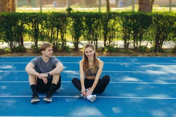 Couple doing sport together on the stadium. Having rest after morning run - Photo, Image