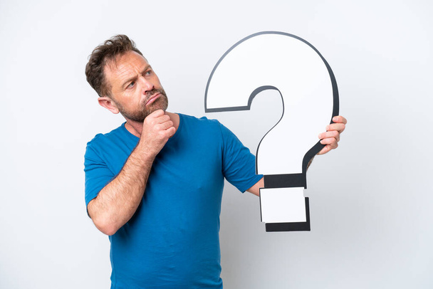 Middle age caucasian man isolated on white background holding a question mark icon and having doubts - Фото, изображение