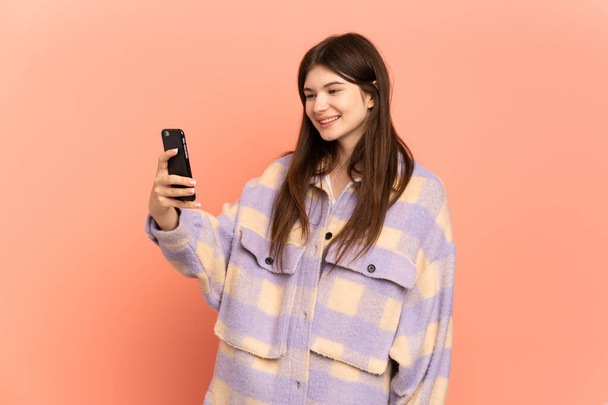 Young Ukrainian girl isolated on pink background making a selfie - Valokuva, kuva