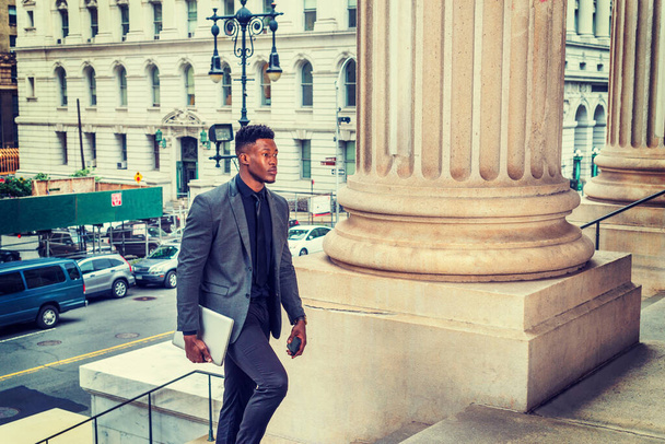 Uomo d'affari afroamericano che viaggia, lavora a New York, indossa giacca alla moda, cravatta, trasporta computer portatili, entra in un palazzo di uffici vintage dalla strada. effetto filtrato - Foto, immagini