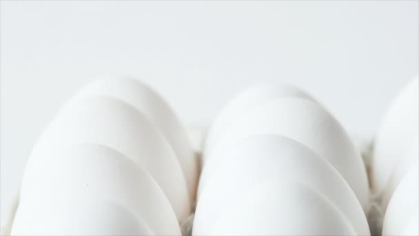 Яйця в коробці, обертаються білими курячими яйцями в коробці. Курячі білі свіжі сирі яйця в яєчній тарі
 - Кадри, відео
