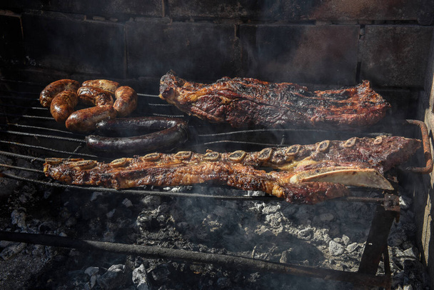 Barbecue, grilled sausages and cow meat , traditional argentine cuisine - Foto, imagen