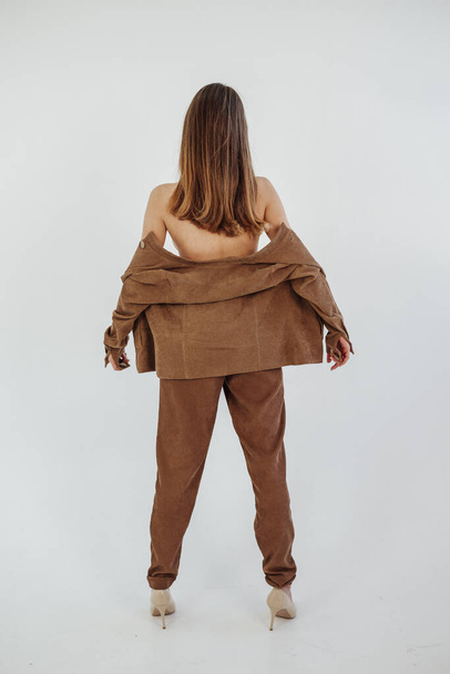 Красива модель позує в коричневому костюмі на фотосесії в студії
 - Фото, зображення