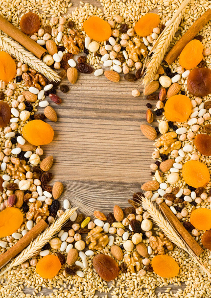 Ingrediënten van ashura dessert; walnoot, hazelnoten, tarwe, bonen, abrikozen, druiven en kikkererwten op houten ondergrond ontworpen als een frame met kopieerruimte - Foto, afbeelding