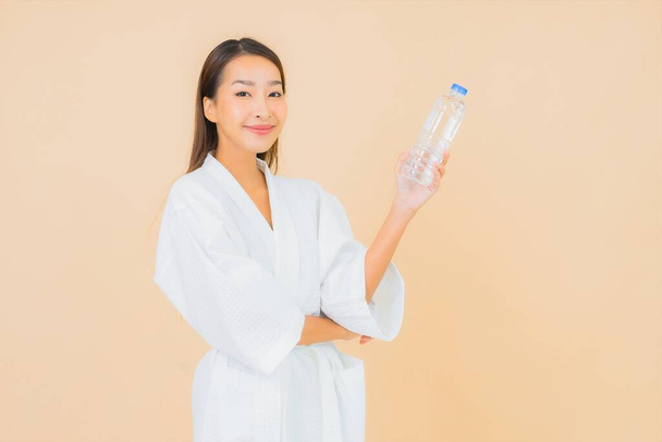 Портрет красивая молодая азиатская женщина с бутылкой воды для питья на цветном изолированном фоне - Фото, изображение