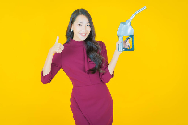 Portret mooie jonge aziatische vrouw feul gas pomp op kleur achtergrond - Foto, afbeelding