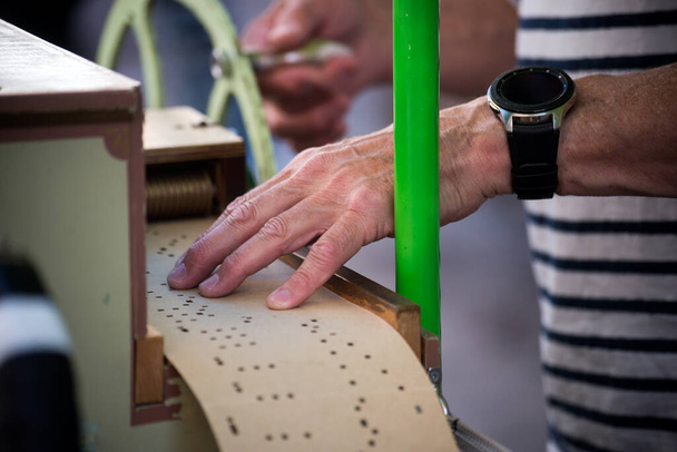Closeup of hands of man playing with a barrel organ in the street  - Фото, изображение