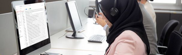 La jeune femme d'affaires est musulmane ou islam et l'équipe porte un casque avec une ethnicité diversifiée tandis que le centre d'appels soutient le service à la clientèle et vérifie l'e-mail sur l'ordinateur au bureau, concept d'entreprise. - Photo, image