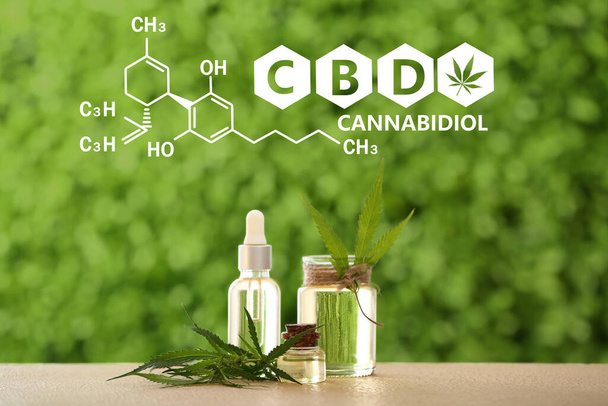 Bottles of CBD oil and leaves on table outdoors - 写真・画像