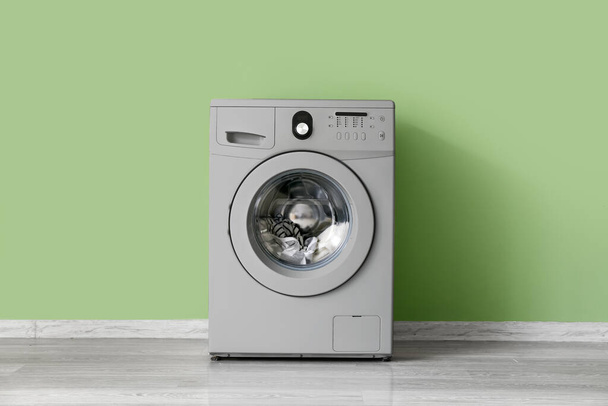 Modern washing machine near green wall - 写真・画像