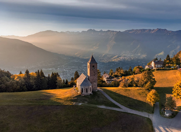 Hafling, Olaszország - Légi kilátás a hegyi templom Szent Katalin (Chiesa di Santa Caterina) közelében Hafling - Avelengo egy meleg őszi naplemente az olasz Dolomitok Dél-Tirolban a háttérben - Fotó, kép