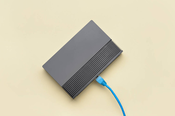 Modern wi-fi router and internet cable on beige background - Valokuva, kuva