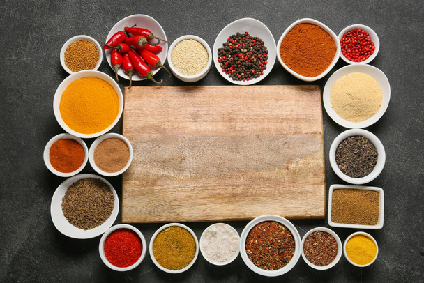 Set of different aromatic spices and wooden board on dark background - Photo, Image
