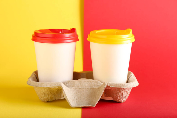 Holder with takeaway paper cups on color background - Φωτογραφία, εικόνα