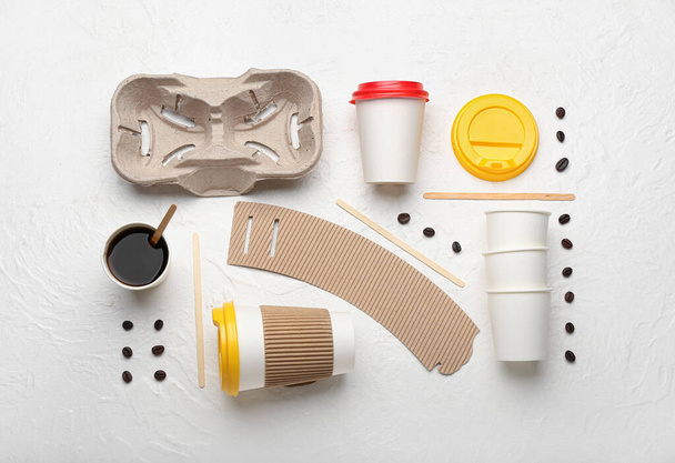 Takeaway paper cups, coffee beans, holder and spoons on white background - Foto, afbeelding