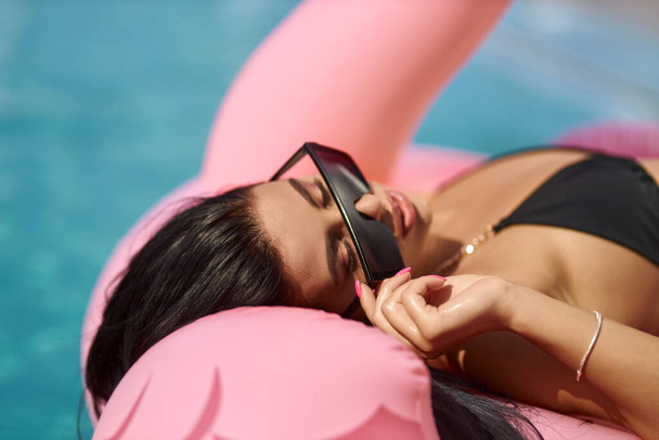 Above view of relaxed woman in sunglasses chilling on pink float outdoor. - Fotoğraf, Görsel