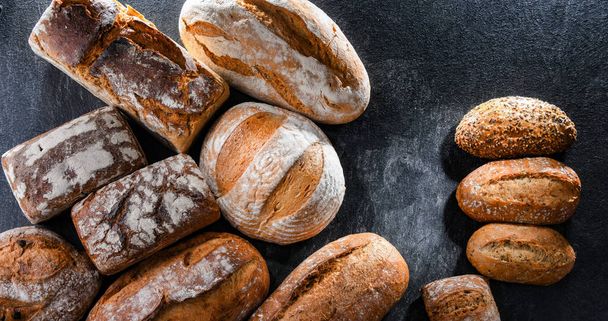 Assorted bakery products including loafs of bread and rolls - Фото, изображение