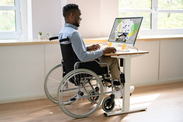 Worker In Wheelchair Searching For Real Estate On Computer At Work - Foto, Bild