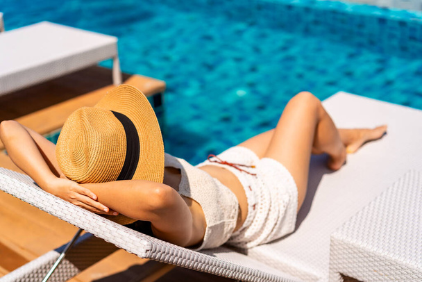 Young woman traveler relaxing at the resort pool while traveling for summer vacation - Photo, Image
