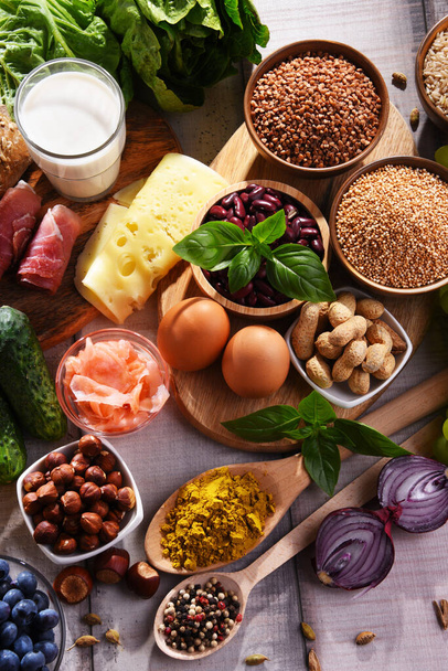 Σύνθεση σαλονιού με διάφορα βιολογικά προϊόντα τροφίμων σε ξύλινο τραπέζι κουζίνας. - Φωτογραφία, εικόνα