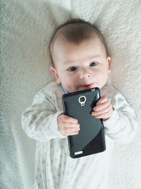 Piccolo bambino che tiene smartphone a letto
 - Foto, immagini