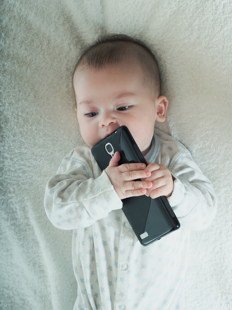 Small baby boy holding smartphone in bed - Photo, Image