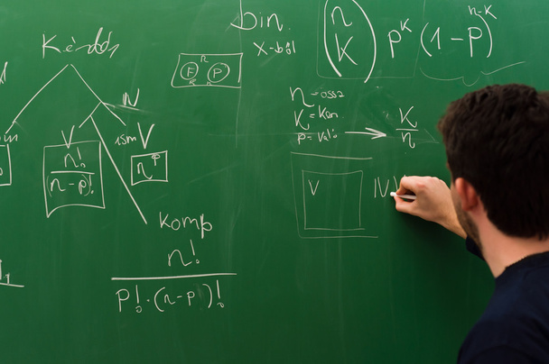 Young student writing formulas on green chalk board - Zdjęcie, obraz