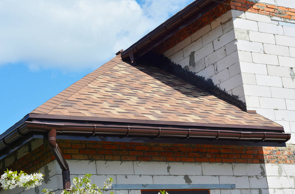 Asfalt kiremitler çatı inşaatı. Ev asfalt kiremitler köşe çatı çatı su geçirmez çatı oluğu sistemi.  - Fotoğraf, Görsel