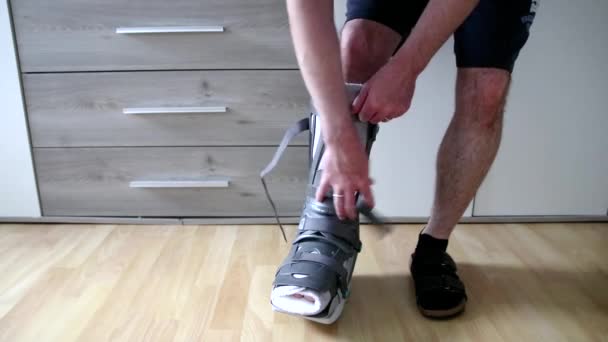 Man unpacking and unboxing foot first steps after Achilles tendon rupture operation with moon boot showing stitches and operation transection walks barefoot with pain and partial weight bearing PWB - Metraje, vídeo