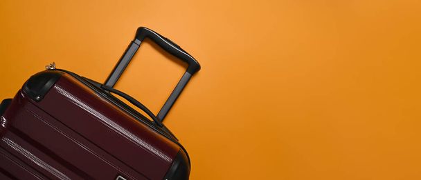 A suitcase on orange background with cop space. Preparing for the summer vacations - Foto, imagen