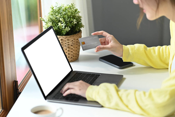 Shot of young woman holding credit card and using computer laptop for payment online or shopping online - Foto, Imagen
