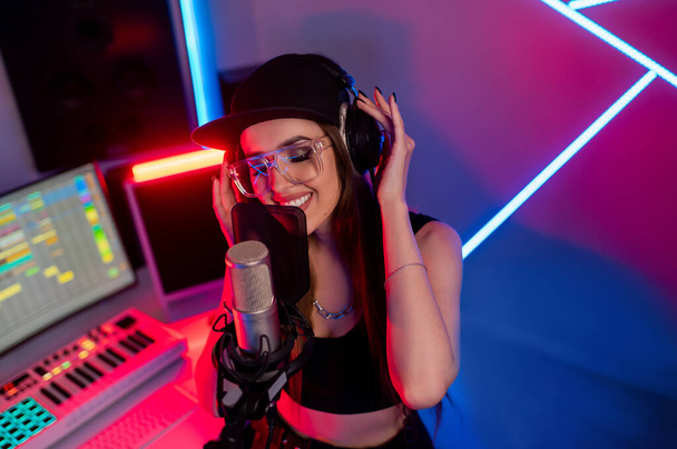 Belle fille élégante chantant dans un microphone dans un studio d'enregistrement  - Photo, image