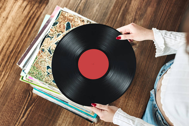 Playing vinyl records. Listening to music from vinyl record player. Retro and vintage music style. Woman holding analog LP record album. Stack of old records. Music collection. Music passion - Fotó, kép