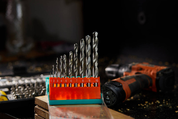 Close up of a metal drill bit set at workshop, carpenter chooses a drill for drilling a wooden block. - Foto, afbeelding