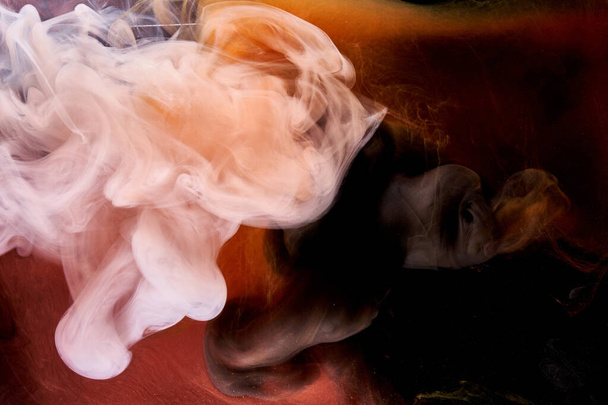 Oranje witte rook op zwarte inkt achtergrond, kleurrijke mist, abstracte wervelende aanraking oceaan, acrylverf pigment onderwater - Foto, afbeelding