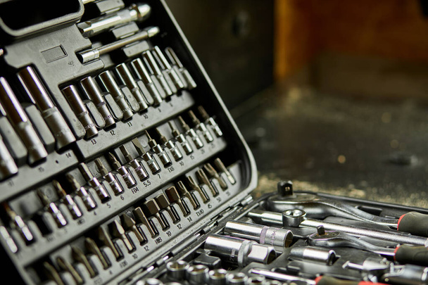 Open set box met werktuigen verschillende soorten metalen stalen koppen en bits in de werkplaats, verwisselbare schroevendraaierset. - Foto, afbeelding