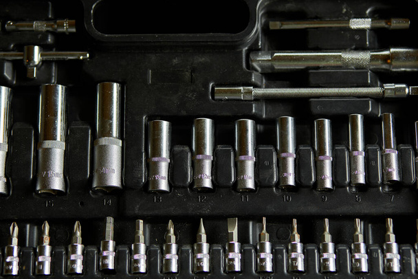 Open set box met werktuigen verschillende soorten metalen stalen koppen en bits in de werkplaats, verwisselbare schroevendraaierset. - Foto, afbeelding