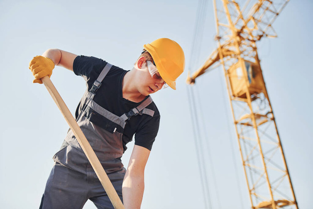 Using showel. Construction worker in uniform and safety equipment have job on building. - Fotografie, Obrázek