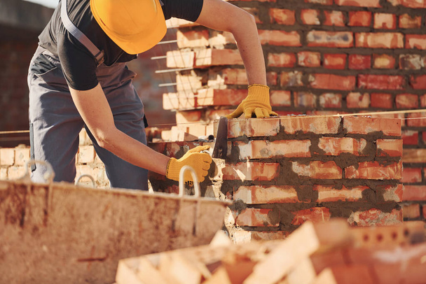 Busy with brick wall. Construction worker in uniform and safety equipment have job on building. - 写真・画像