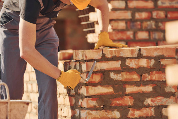 Busy with brick wall. Construction worker in uniform and safety equipment have job on building. - Photo, Image