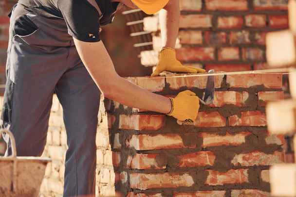 Busy with brick wall. Construction worker in uniform and safety equipment have job on building. - Φωτογραφία, εικόνα