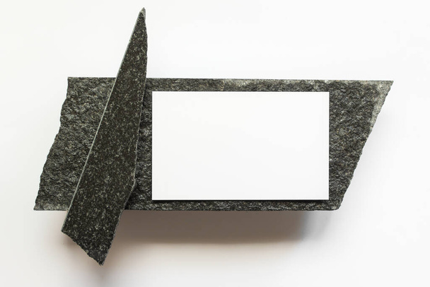 Mockup template with white horizontal card on black natural raw stone on white background. - Zdjęcie, obraz