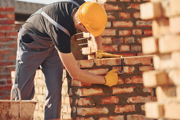 Busy with brick wall. Construction worker in uniform and safety equipment have job on building. - 写真・画像