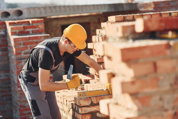 Measures of brick wall. Construction worker in uniform and safety equipment have job on building. - 写真・画像