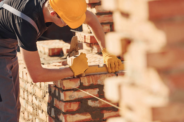 Measures of brick wall. Construction worker in uniform and safety equipment have job on building. - Foto, afbeelding