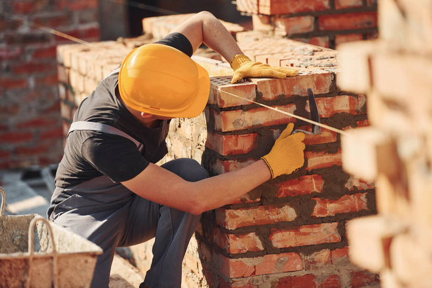 Measures of brick wall. Construction worker in uniform and safety equipment have job on building. - Valokuva, kuva