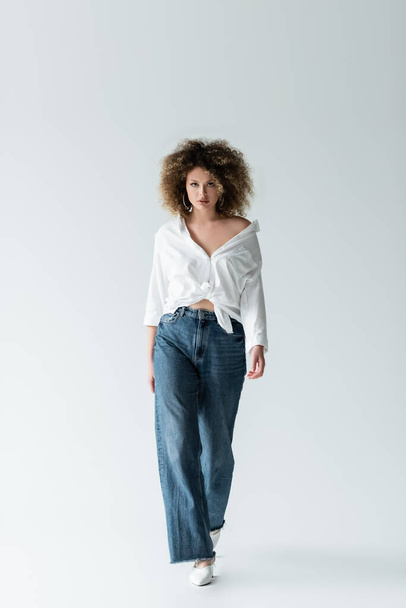 Curly woman in blouse walking on white background  - Fotografie, Obrázek
