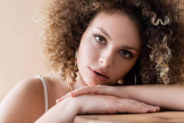 Portrait of curly woman looking at camera isolated on beige  - Photo, image