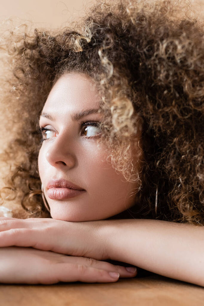 Young curly model looking away isolated on beige  - Photo, Image