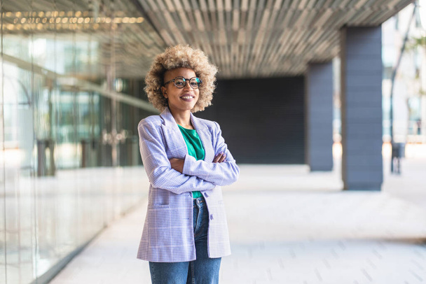 Happy successful black female professional smiling at camera. Young African American business woman with arms crossed standing in the office - Photo, image